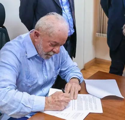 Lula assinando documento.