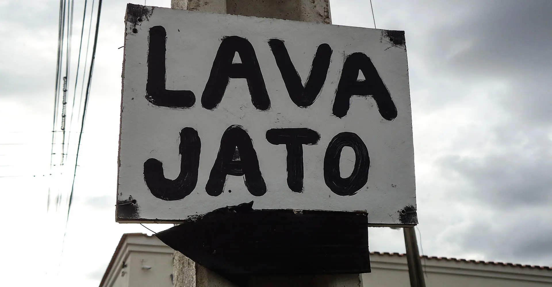 Placa fixada em poste de energia com a palavra escrita em português, LAVA JATO. LAVA JATO é uma operação da polícia brasileira para combater a corrupção