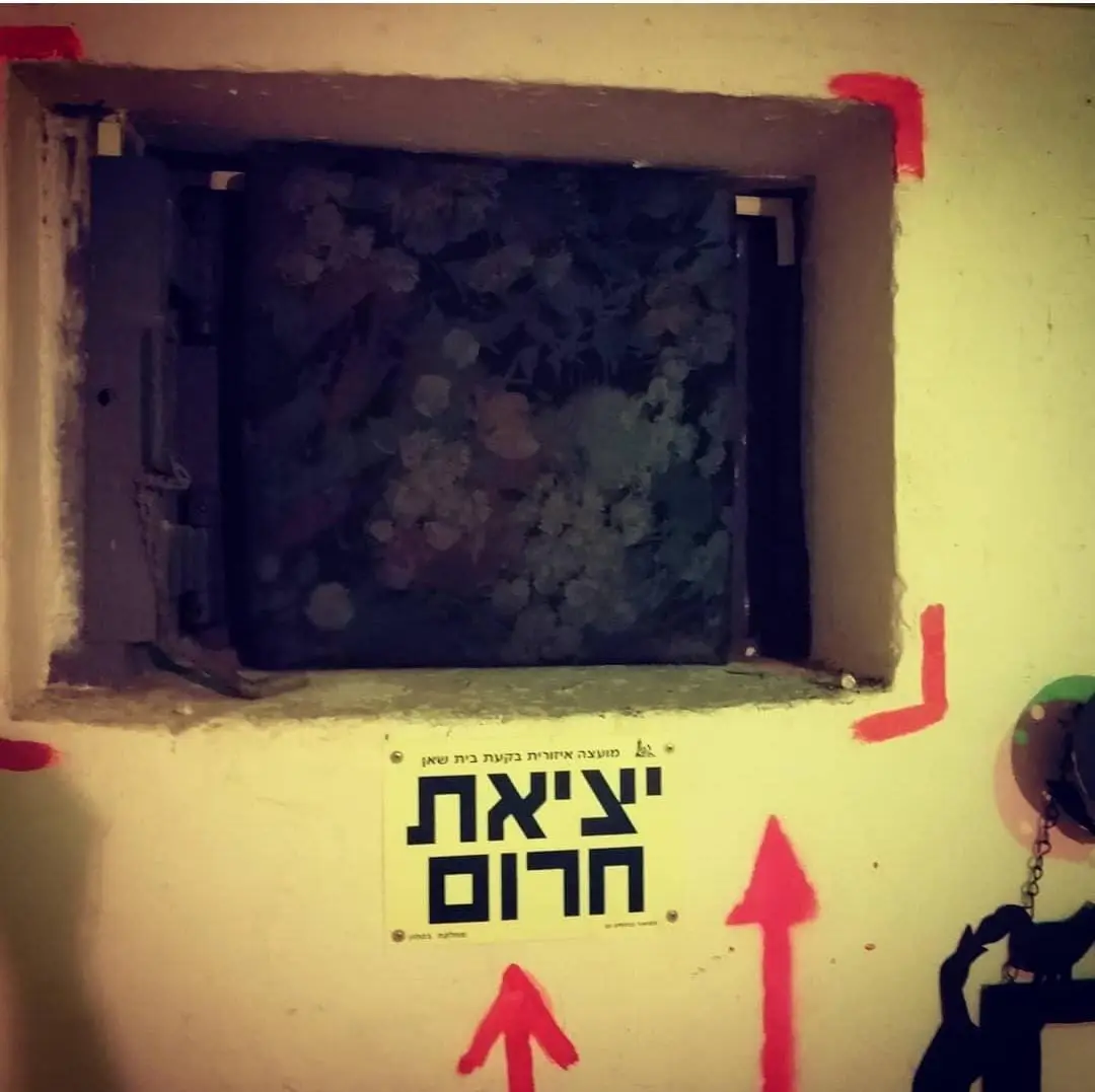 Janela de um "bunker" compartilhado, fechada com porta de correr de aço e pintada nas laterais de vermelho para identificação no escuro 