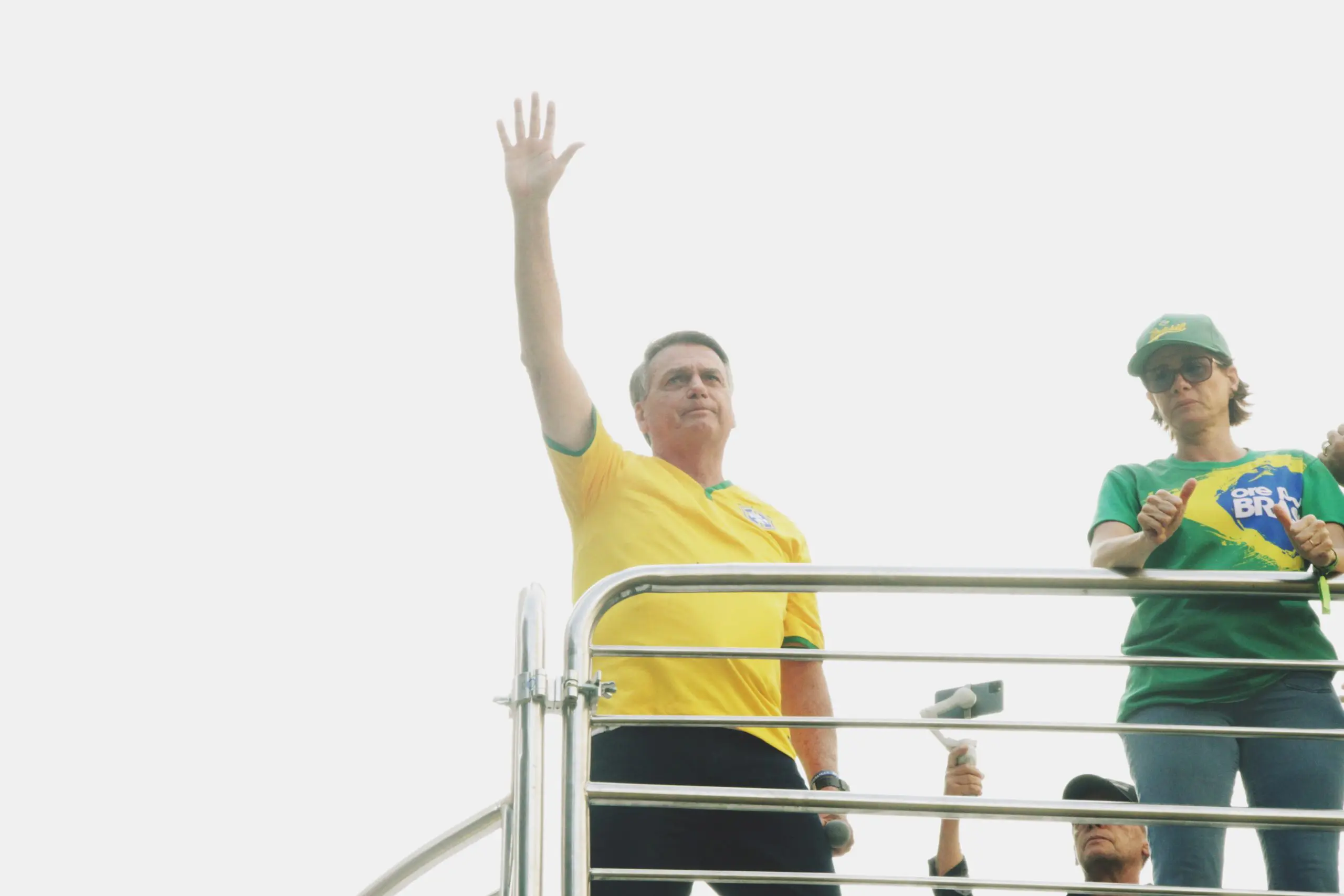 O ex-presidente Jair Bolsonaro, com o braço erguido para o público, durante uma manifestação popular