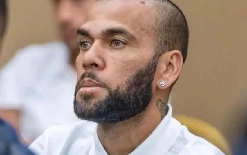 Ex-jogador Daniel Alves veste camisa branca, barba ralada e brinco