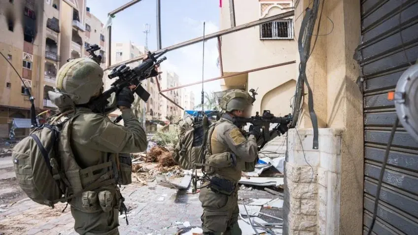 Soldados das Forças de Defesa de Israel em posição de combate frente a um prédio com terroristas do Hamas