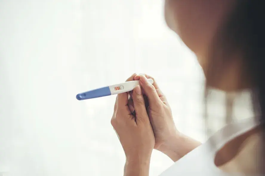 Mãos de uma mulher segurando teste de gravidez