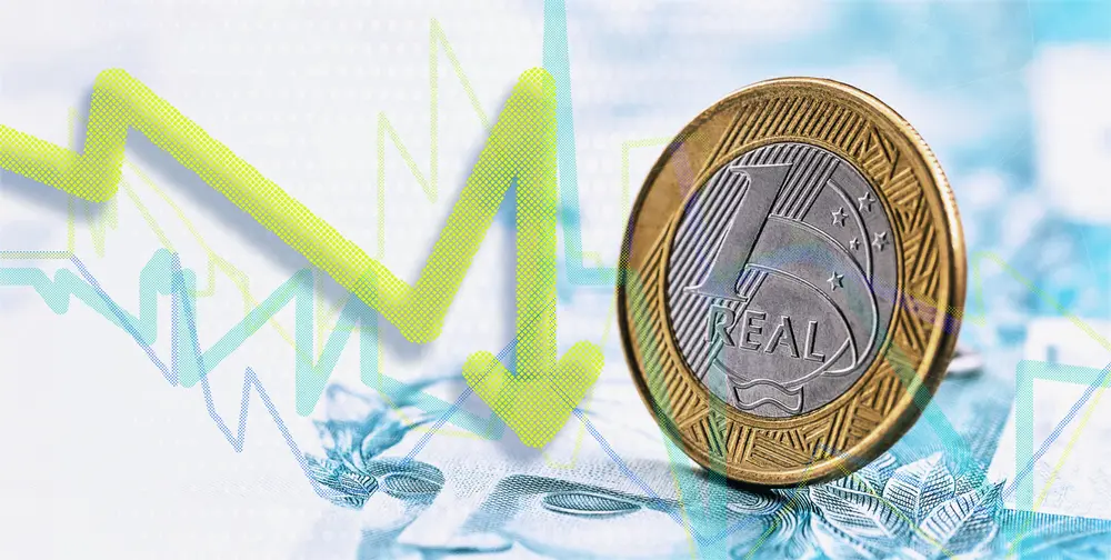 Moeda de um real e seta para baixo, para ilustrar a desvalorização da moeda