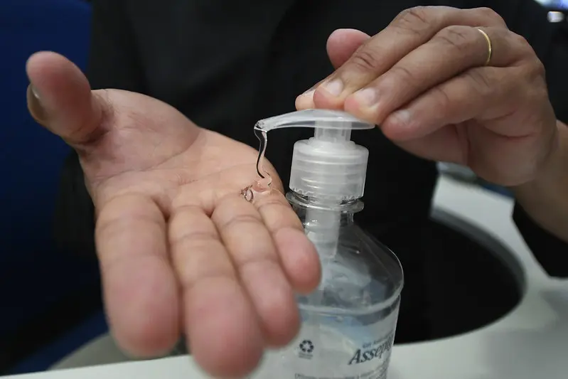 Uma pessoa de pele parda usa álcool gel em suas mãos. Apenas esse produto será permitido pela Anvisa