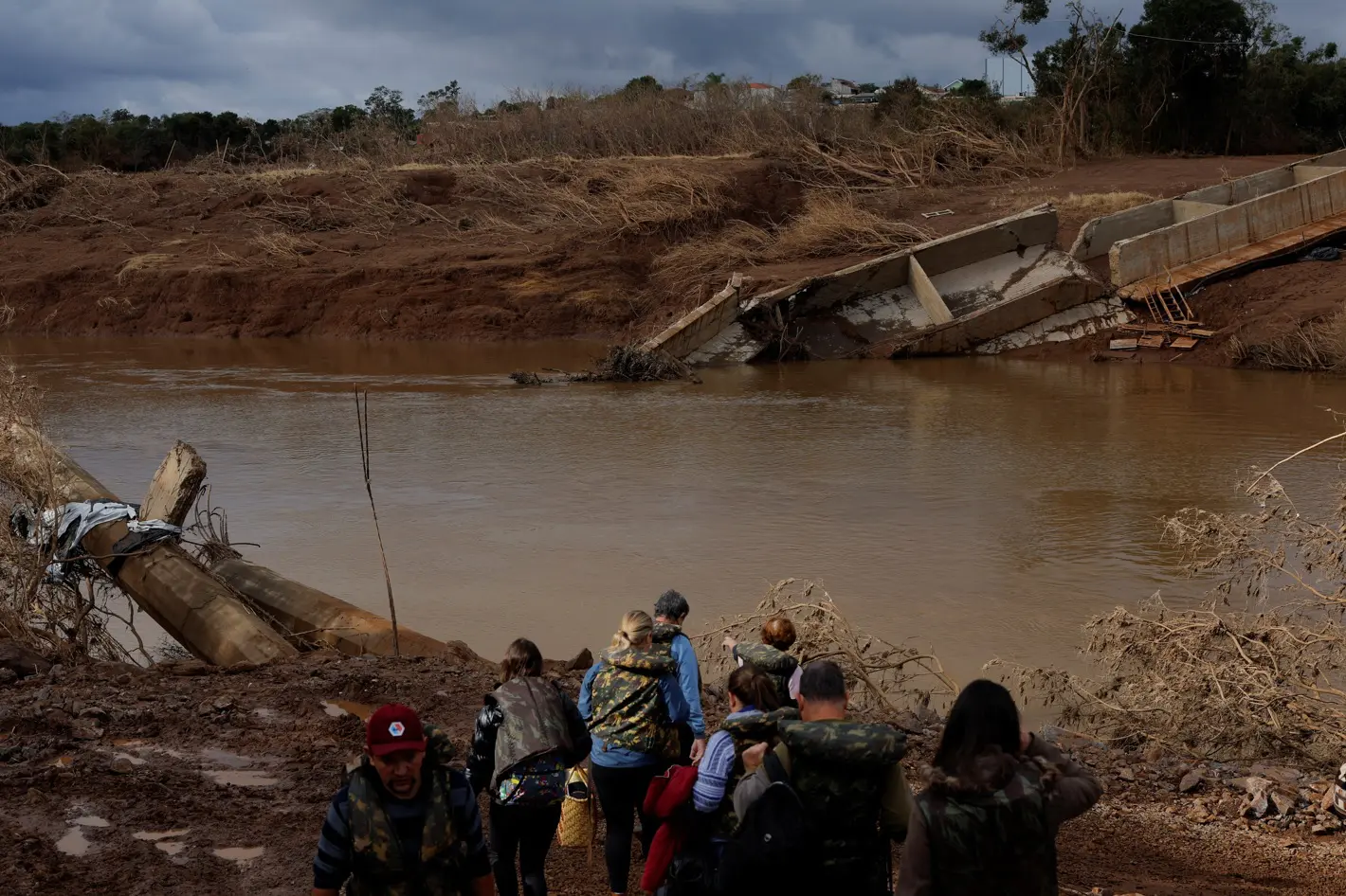 Pessoas caminham perto de uma ponte que desabou durante a cheia do Rio Taquari, em Arroio do Meio, no Rio Grande do Sul - 20/5/2024 | Foto: Amanda Perobelli/Reuters
