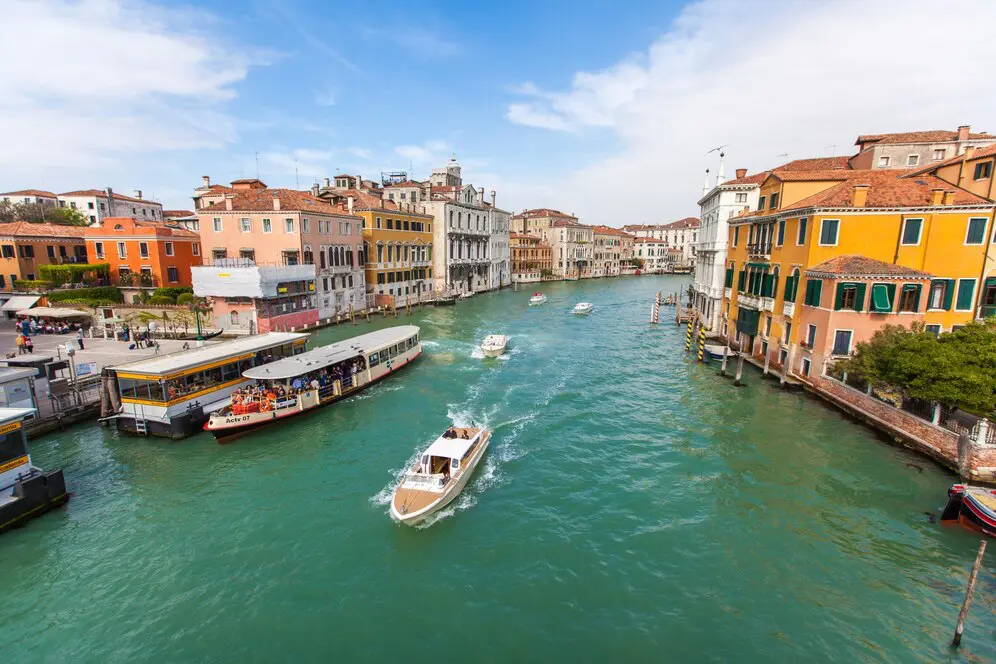 Veneza na Itália - um rio com casas em volta e um barco próximo de um cais