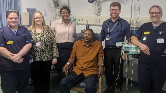 Primeiro paciente a testar vacina contra o câncer ao lado de equipe médica na Inglaterra