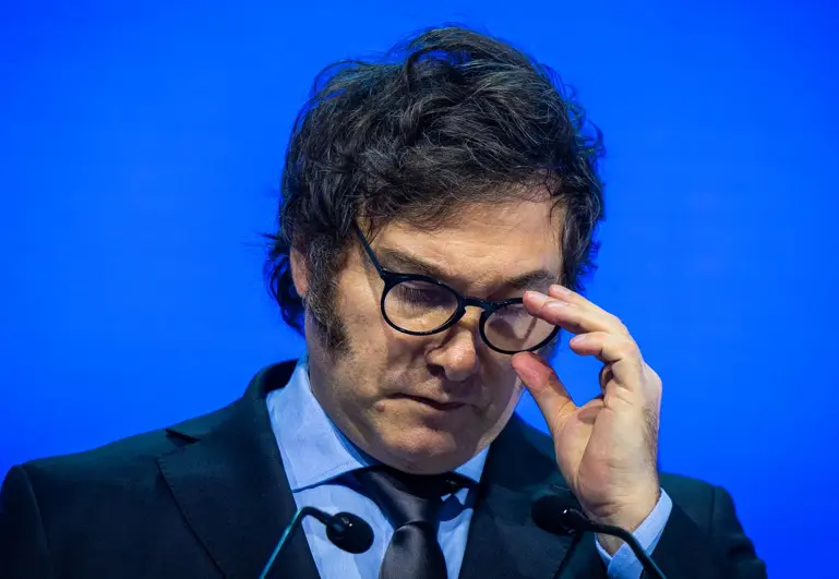 Javier Milei usa terno preto e segura óculos enquanto discursa