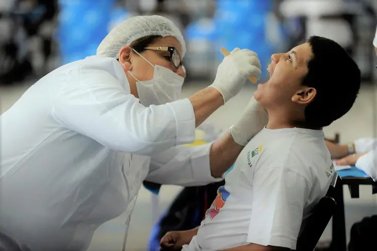 Dentista atende jovem dentro de escola pública