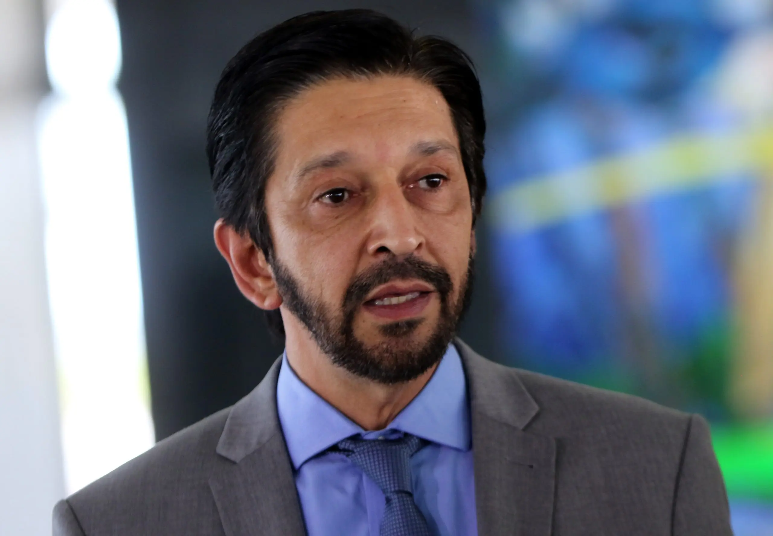 Prefeito Ricardo Nunes, de camisa azul e blazer cinza com fundo desfocado em azul