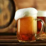 Overflowing,Foam,Head,From,Beer,Glass,Pint,,Placed,On,Wood