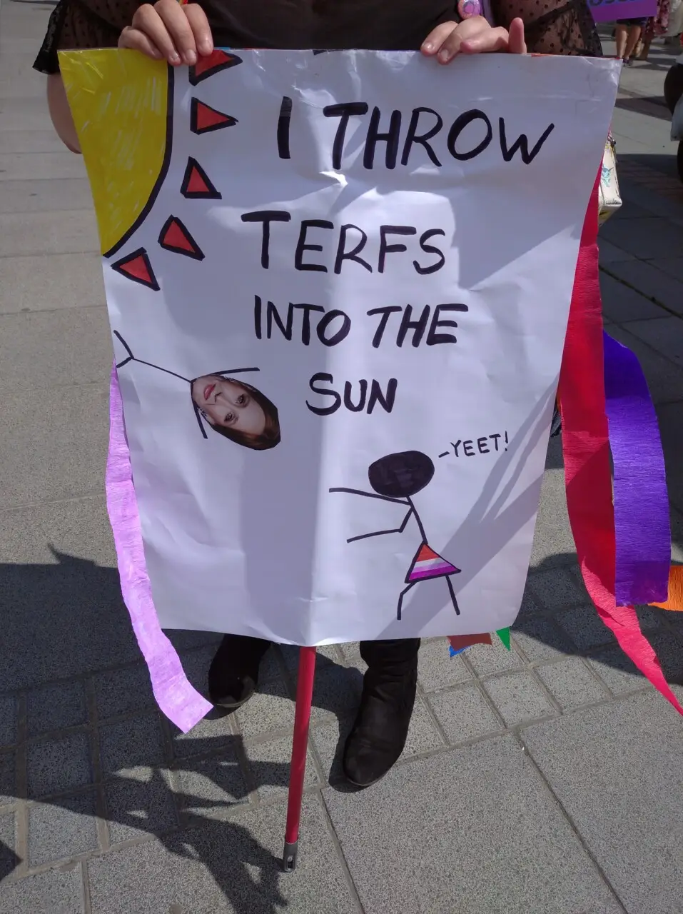 Manifestante segura cartaz escrito "Eu jogo Terfs no sol"