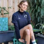 Atleta trans Lexi Rodgers sentada com plantas atrás.