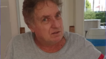 Saul Klein, filho do fundador da Casas Bahia, olha de frente para a câmera. Ele está de camiseta cinza. Atrás, uma sala com móveis comuns.
