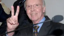 Mário Jorge Lobo Zagallo, vestido de terno preto e camisa azul, gesticulando com o sinal de 'paz e amor'