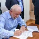 Lula assinando documento.