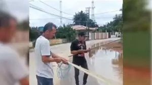 Moradores improvisam pescaria em alagamento de rua para chamar a atenção do prefeito.