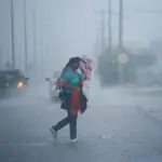 previsão do tempo chuva norte sul Brasil - mulher com guarda-chuva atravessa rua