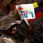 Guiana | Um membro da Milícia Bolivariana da Venezuela ergue uma bandeira da Venezuela, durante o evento de encerramento da campanha, antes do referendo sobre a região de Essequibo | Leonardo Fernández Viloria/Reuters