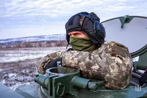 Um militar ucraniano, com o rosto coberto, em um tanque de guerra