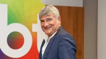 Foto do narrador Cléber Machado ao lado do logo do SBT