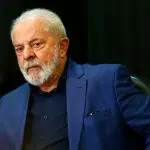 O presidente Luiz Inácio Lula da Silva, de terno azul escuro e camisa preta, olha de soslaio para a câmera que está à sua frente. Recentemente, o chefe do Executivo comparou Israel a Hitler - governo lula indígena