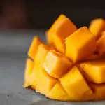 Uma manga cortada em pequenos cubos, sobre uma superfície cinza