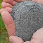 Um cidadão segura pó de rocha nas mãos. O material pode ser usado como fertilizante