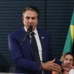 O ministro Camilo Santana, de terno azul, durante reunião com secretários. Atrás, a bandeira do Brasil