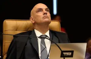 Indivíduo sério em tribunal, vestido com toga preta e gravata listrada, associado a Alexandre de Moraes