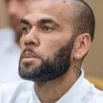 Ex-jogador Daniel Alves veste camisa branca, barba ralada e brinco