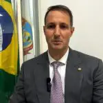 O deputado federal Guilherme Derrite, de terno cinza escuro, camisa branca e grava roxa