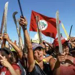Integrantes do MST seguram facas e bandeira do movimento