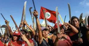 Integrantes do MST seguram facas e bandeira do movimento