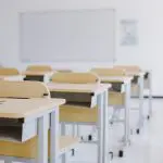 Sala de aula com carteiras e fundo branco