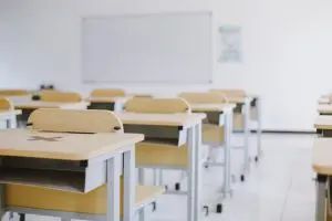 Sala de aula com carteiras e fundo branco