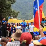 Maria Corina Machado veste uma roupa azul enquanto discursa para eleitores venezuelanos
