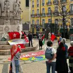 Pessoas segurando a bandeira da palestina em frente a um monumento em Lisboa, Portugal. Ato pró-democracia do Partido dos Trabalhadores fica vazio em várias cidades do Brasil e algumas do exterior.