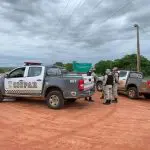 Policiais em Mossoró realizam as buscas pelos fugitivos do presídio de Mossoró. Duas viaturas paradas em um chão de barro, com policiais ao redor