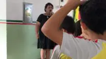 A servidora, de vestido preto, doutrinando alunos