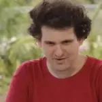 O empresário Sam Bankman-Fried, de camiseta vermelha. Ele é branco e possui um cabelo mais volumoso