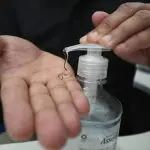 Uma pessoa de pele parda usa álcool gel em suas mãos. Apenas esse produto será permitido pela Anvisa