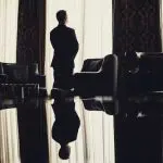 Homem sozinho em uma sala olhando pela janela