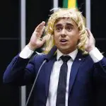 Nikolas Ferreira de terno e peruca loira, ironizando ao falar que "se sente mulher", em 8 de março, Dia Internacional da Mulher