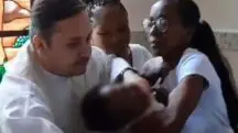 padre dá puxão em criança durante batismo