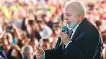 Presidente Lula usa terno preto e discursa com um microfone na mão