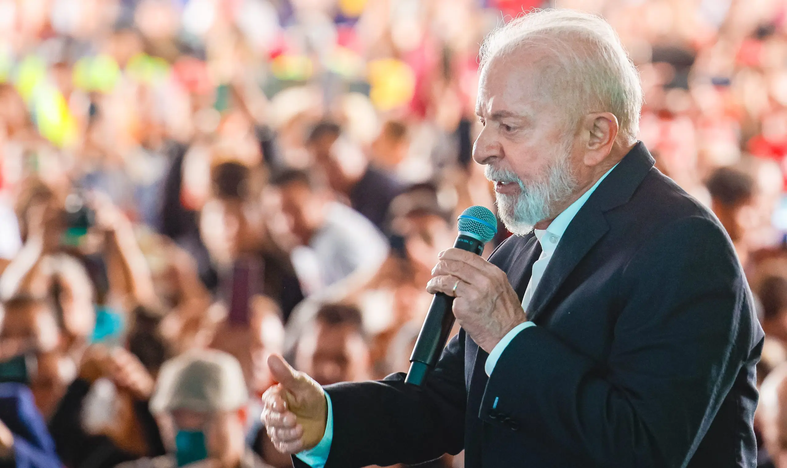 Presidente Lula usa terno preto e discursa com um microfone na mão