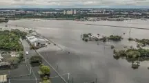Pista do aeroporto Salgado Filho, em Porto Alegre (RS), tomada pela água; ao fundo, a Arena do Grêmio