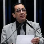 Jorge Kajuru veste terno cinza, camisa social preta, gravata cinza, óculos e segura papel durante discurso no Plenário